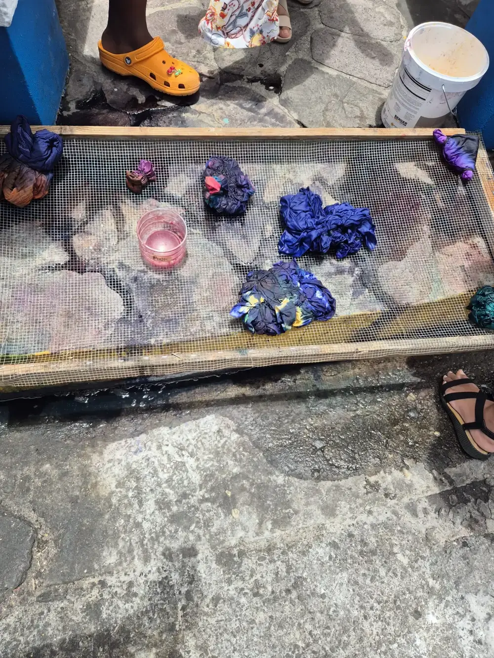 Dyed Adire fabric bundles drying on a mesh rack