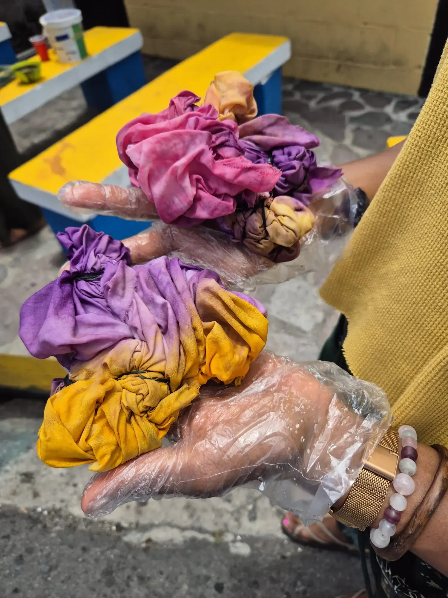Freshly dyed bundles of Adire fabric in pink, purple, and gold