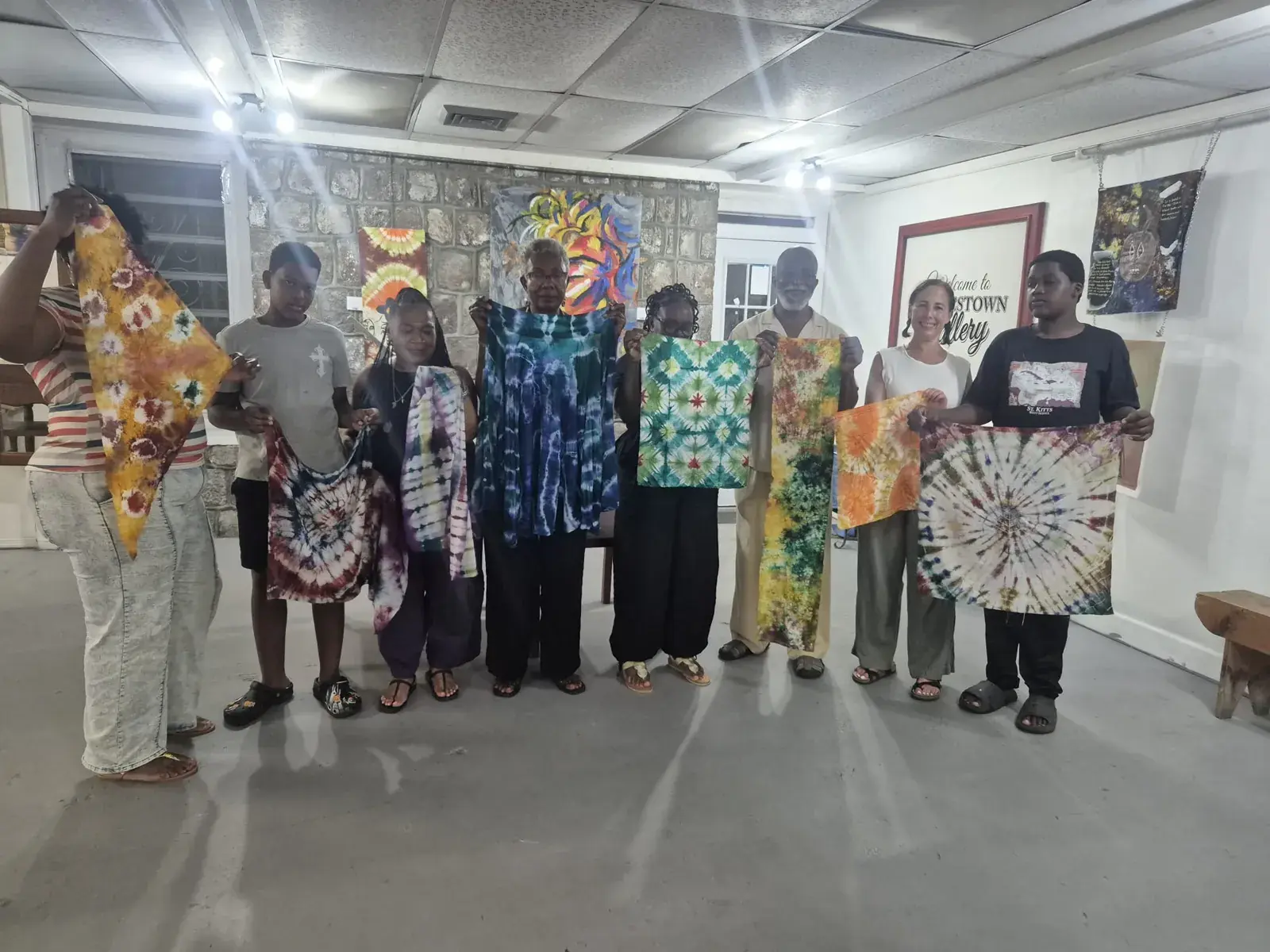 Workshop participants holding up their finished Adire tie-dye pieces at Charlestown Gallery